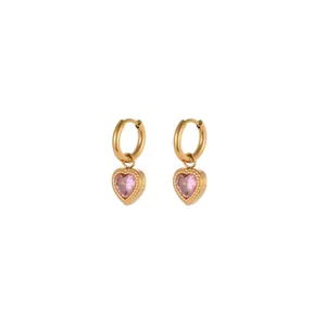 Detalle de pendientes de aro en acero dorado con colgantes de corazón rosa y cristal