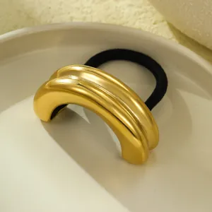 Detailed macro view of the glossy golden finish and curved shell texture of the hair tie.