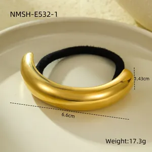 Close-up of minimalist curved 18k gold-plated metal hair tie on ceramic plate.