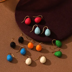 Vue détaillée de boucles d'oreilles en émail coloré en forme de goutte avec crochets dorés.