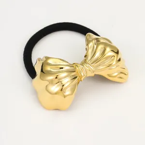 High-quality close-up of a gold metallic bow hair tie featuring a black elastic band