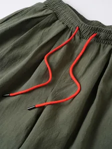 Detalle de los pantalones casuales de lino y algodón verde oliva con cordón naranja vivo