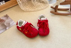 Detailed view of red children's German army trainers with cute floral accents and soft soles.