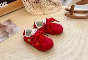Detail of red children's German trainer shoes featuring flower embroidery and soft soles