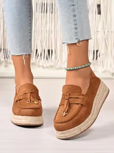 Close-up of brown suede platform espadrille loafers with tassel detail and rope sole.