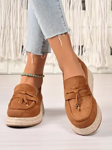 Close-up of women's brown suede platform loafers with espadrille jute soles and tassels