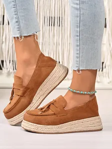 Detail of women's brown suede platform loafers with woven jute sole and tassels