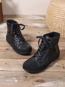 Vista detallada de botines de moda negros lisos con cremallera lateral y cordones