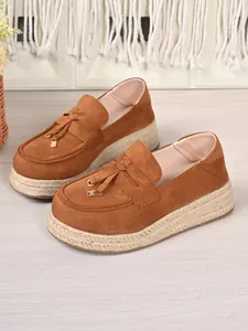 Detailed view of women's brown suede platform loafers with woven jute soles and tassels