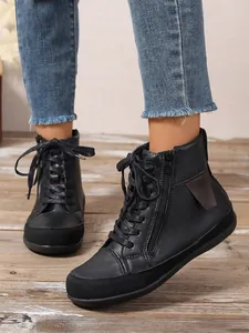 Detalle de botines planos negros para mujer con cremallera lateral y cordones