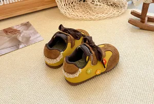 Detailed view of yellow children's sneakers with floral accents and lace trim details.
