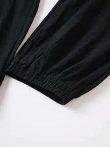 Primer plano de pantalones de algodón y lino negros que muestran el detalle del puño elástico.