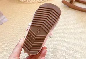 Detail view of the durable non-slip brown rubber sole of a child's sneaker showing size 23.