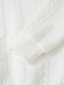 Macro view of white cable knit sweater sleeve showing fine ribbed cuff texture