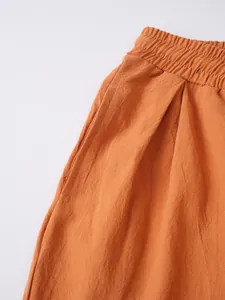 Detalle de pantalón de algodón y lino naranja con cintura elástica y textura de la tela.