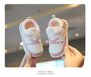 Close-up of pink and white toddler walking shoes with velcro strap and apple detail