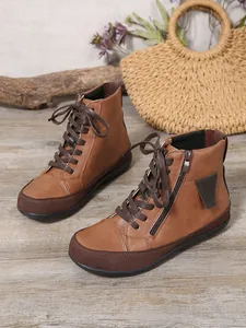 Vista lateral de botines planos marrones con cordones y cremallera