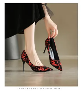 Detailansicht eleganter Stiletto-Pumps mit spitzer Kappe und lebhaftem rotem Abstraktmuster.