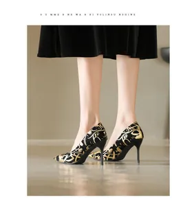 Nahaufnahme eleganter schwarzer Stilettos mit Goldmuster und spitzer Zehenpartie