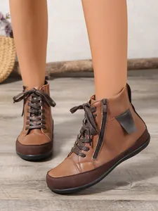 Detalle de botines planos marrones con cremallera lateral y cómodo diseño de cordones