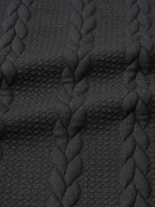 Close-up detail of black cable-knit pattern on men's winter turtleneck sweater fabric