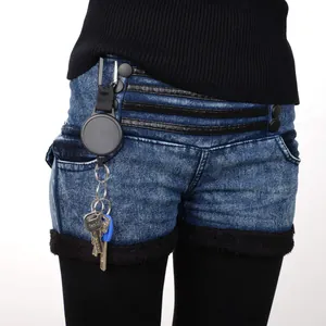Primo piano di un portachiavi a scomparsa fissato al passante di una cintura jeans
