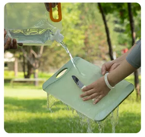 Detail van water dat uit een draagbare opvouwbare waterzak op een snijplank wordt gegoten