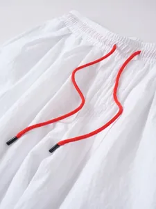 Detalle de primer plano de pantalones de lino y algodón blanco con cordón rojo ajustable