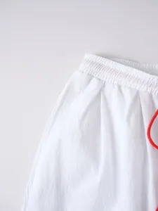 Primer plano de la cintura de pantalones de algodón y lino blancos con cordón rojo.