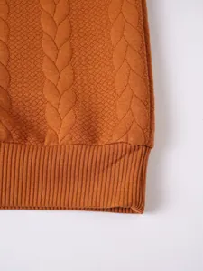 Close-up texture of orange cable knit men sweater featuring detailed ribbed hemline