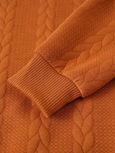 Close-up of rust orange men's knit sweater showing detailed cable pattern and ribbed cuff