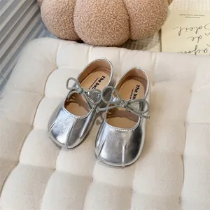 Close-up of silver girls' Mary Jane shoes with soft soles and bow detail.