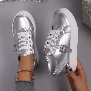 Detail van zilveren metallic platform sneakers met glinsterende kristallen gesp en witte zool