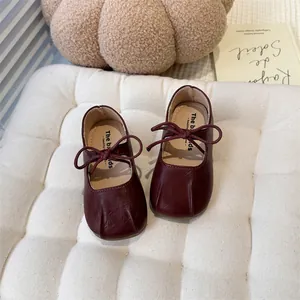 Close-up of burgundy girls' Mary Jane flats with delicate bow and pleated toe detail.