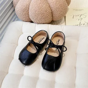 Close-up of black Mary Jane shoes for girls with bow-tie detail on a soft cushion