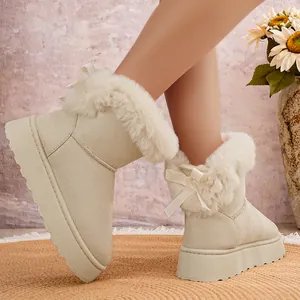 Primer plano de botas de nieve beige con plataforma, borde de pelo sintético y lazo