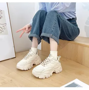 Lifestyle shot of trendy women's chunky platform sneakers in an off-white finish on wood