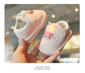 Close-up detail of pink infant walking shoes featuring a glowing monster character and soft sole.