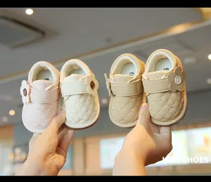 Detailed view of pink and beige infant girl's walking shoes with cute flower accents