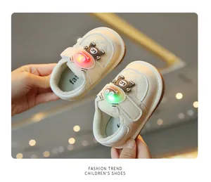 Close-up detail of cream baby walking shoes featuring cute light-up cartoon bear decorations