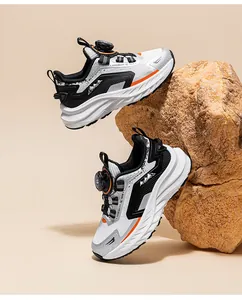 Close-up of kids' black running shoes with rotary buckle system on a rock background