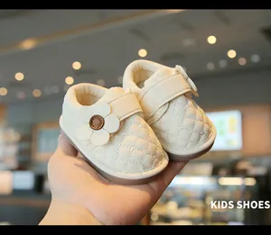 Close-up of cream baby walking shoes with flower detail and quilted texture