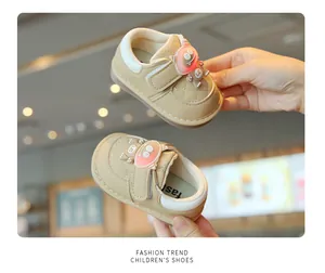Close-up of beige baby light-up walking shoes with cute cartoon monster character detail