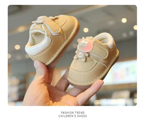 Detail of beige baby light-up walking shoes with a cute monster character on the strap