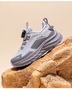 Detail view of grey children's athletic outdoor shoe with rotary dial on a rock