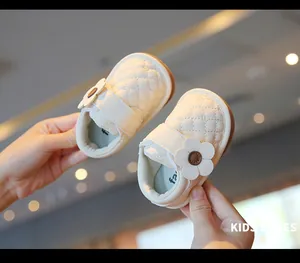 Close-up of cream baby walking shoes with flower detail and soft quilted leather texture.