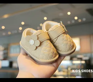 Close-up detail of beige baby walking shoes featuring quilted leather and a large flower