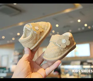 Detailed view of beige baby walking shoes with quilted pattern and flower decoration