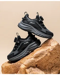 Detailed view of black kids outdoor running shoes with rotary dial closure on a rock
