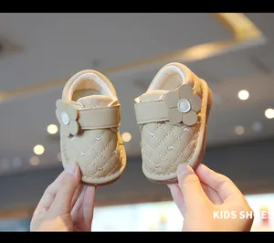 Close-up of beige quilted baby walking shoes with decorative flower and velcro strap